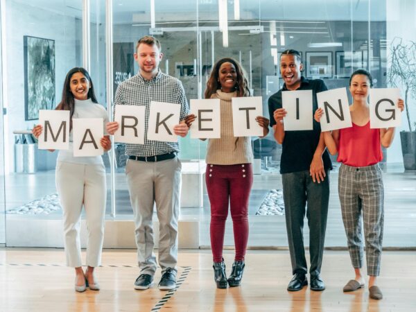 A diverse group of happy colleagues holding a marketing sign, symbolizing teamwork and diversity.