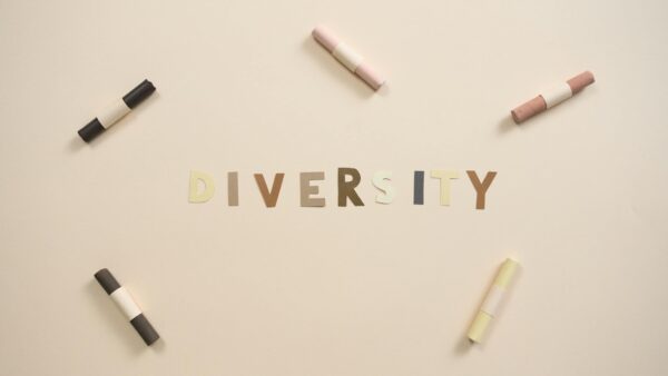 Arrangement of diversity letters and colorful chalks on a white surface.