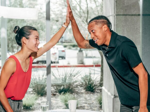 Happy coworkers giving a high five in an office setting, symbolizing teamwork and success.